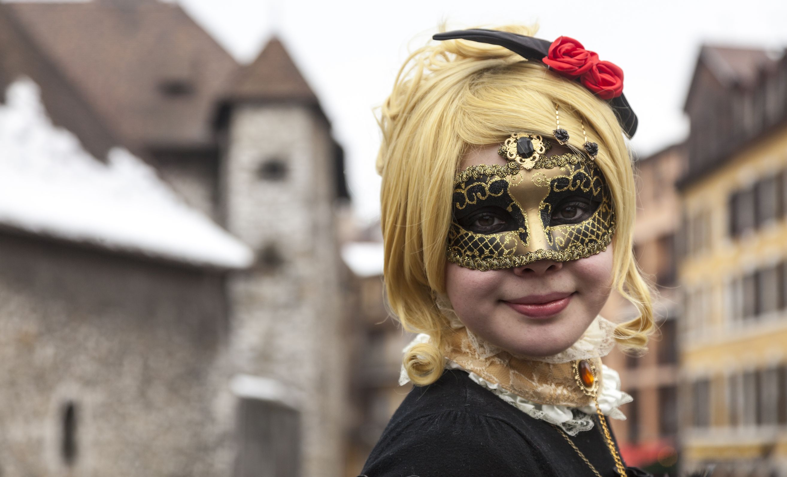 18321492 - annecy, france, february 23, 2013: environmental portrait of a girl in colombina mask posing in front of the palais de l'isle in annecy during a venetian carnival which celebrates the beauty of the real venice.